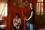 Two women in casual t-shirts, one in black and one in beige, in a cozy wooden interior