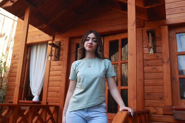 Woman in light green basic t-shirt and jeans standing on a wooden porch