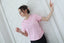 Woman in a pink basic t-shirt with short sleeves, standing by a white geometric wall