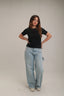 Woman in black short sleeve top and light blue wide-leg jeans, casual fashion style