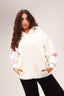 Woman wearing oversized white hoodie with pink accents and black pants, casual style