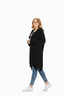 Woman wearing an oversized black knitted cardigan, jeans, and white sneakers on white background.